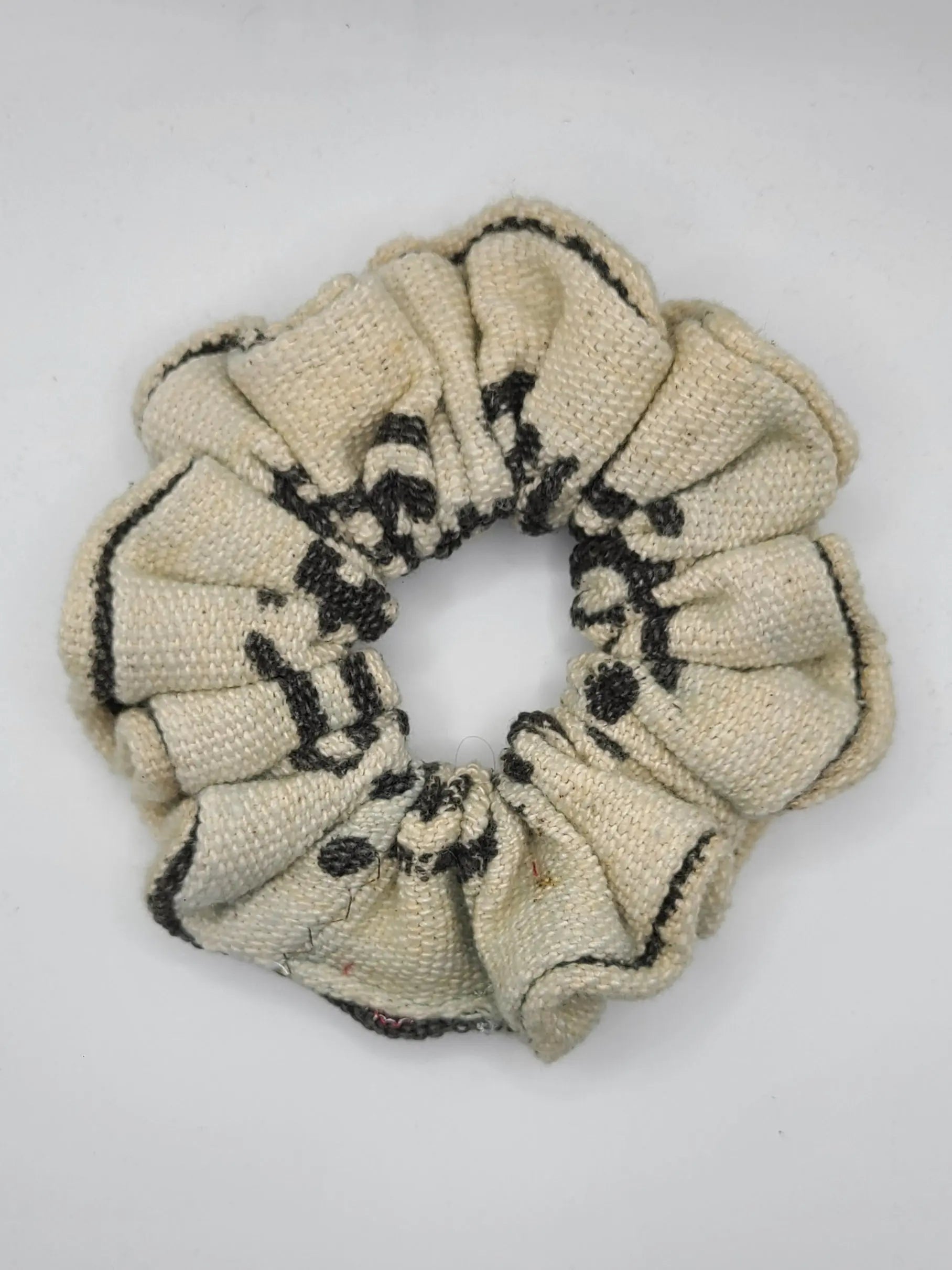 Beige scrunchie with black pattern on a white background