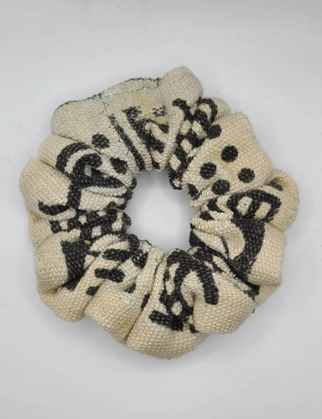 Beige scrunchie with black pattern on a white background