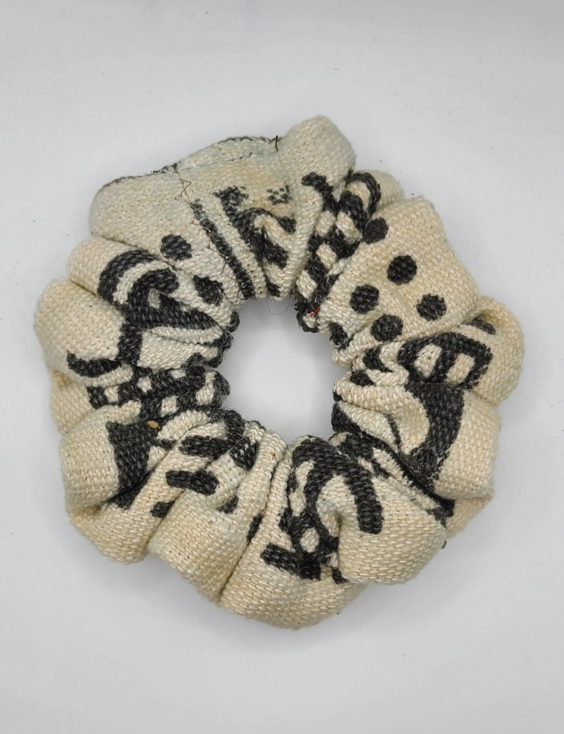 Beige scrunchie with black pattern on a white background