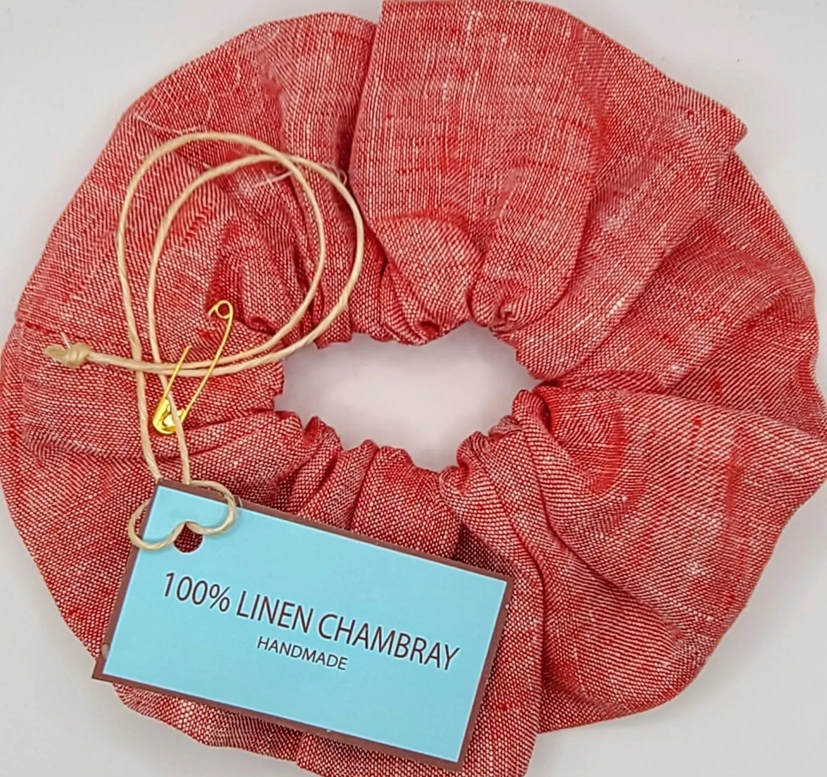 Red linen scrunchie with a blue label on a white background