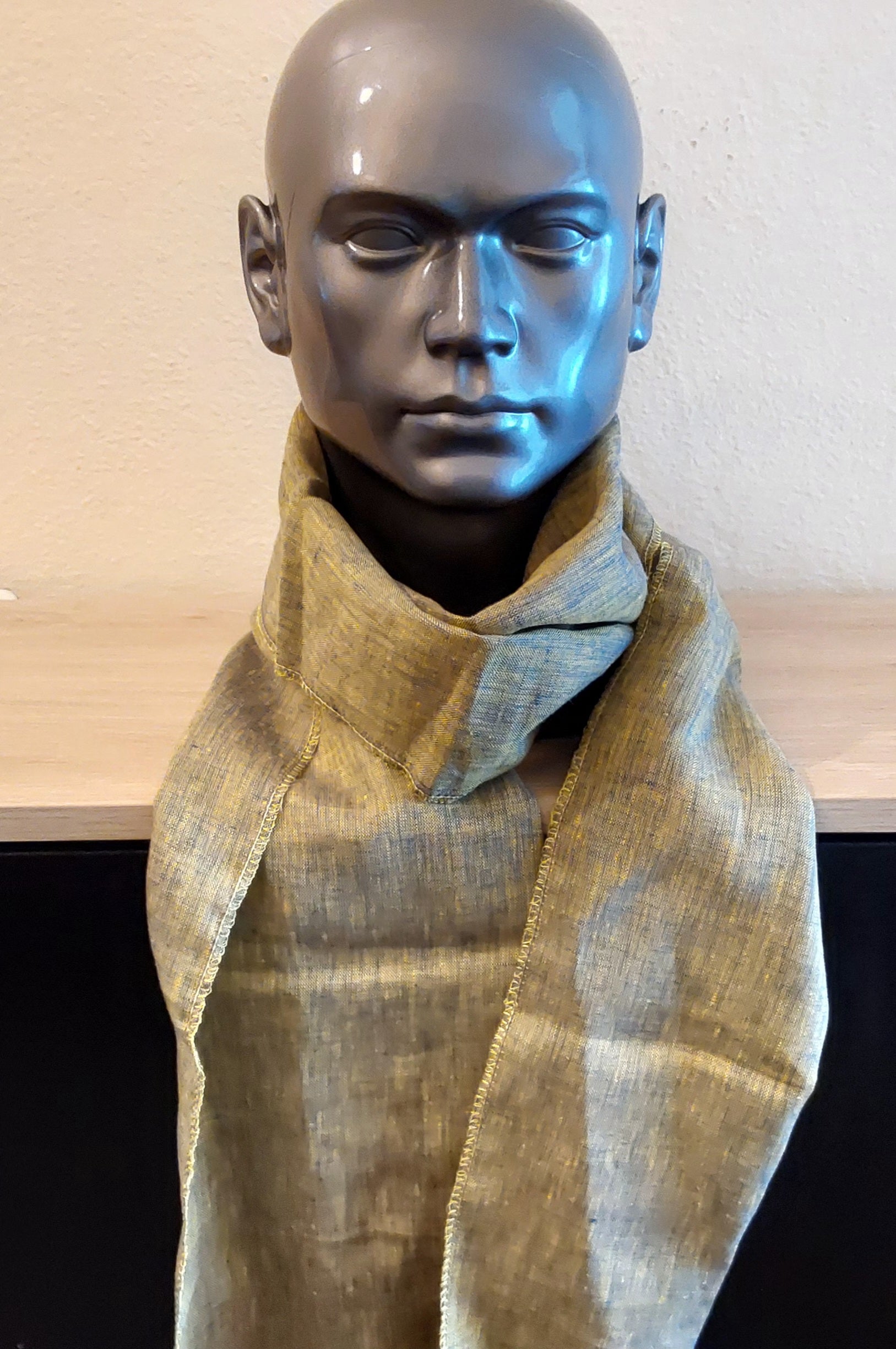 Mannequin wearing a khaki scarf with a neutral background