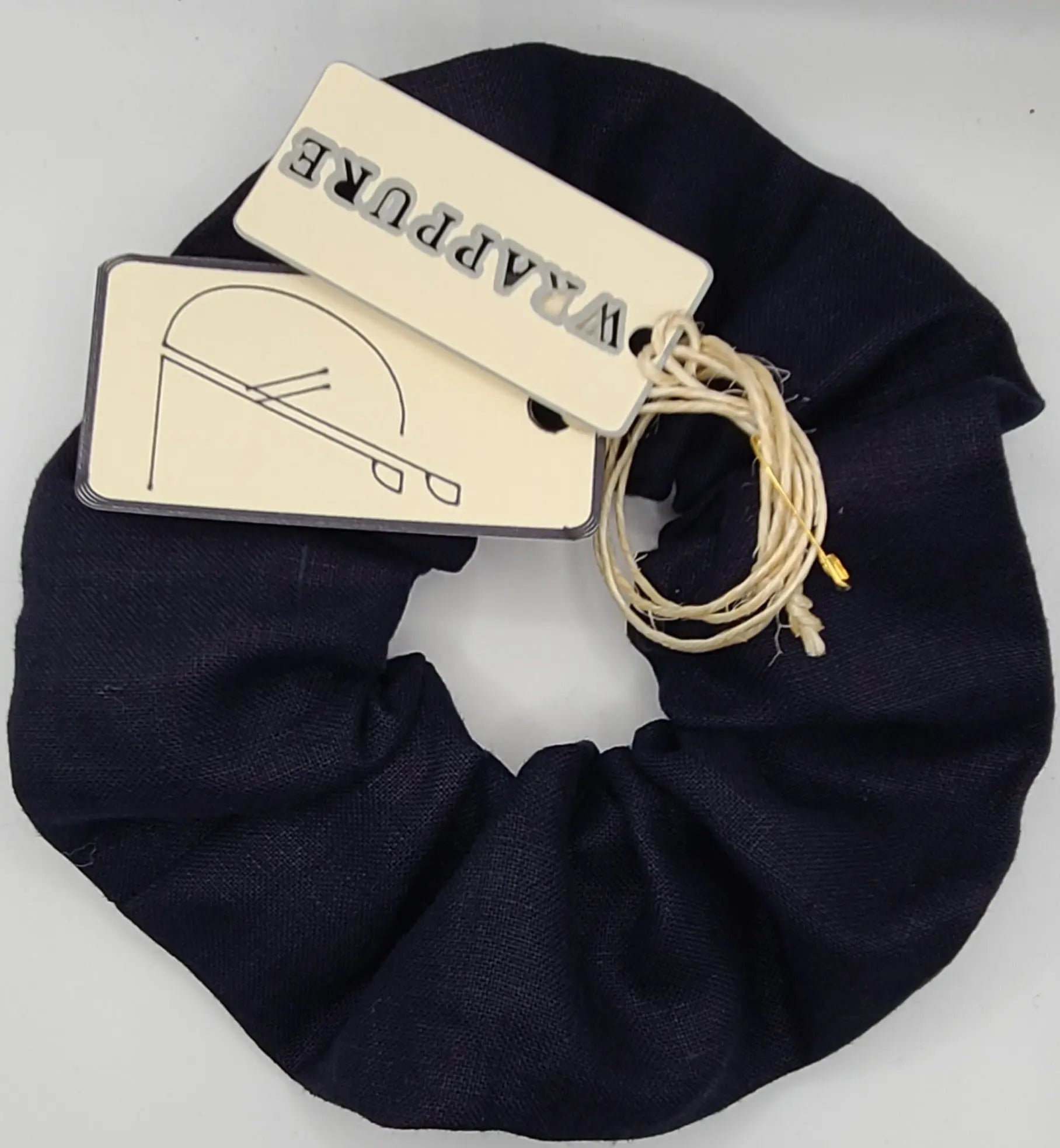 Navy bluescrunchie with a brand tag on a light gray background