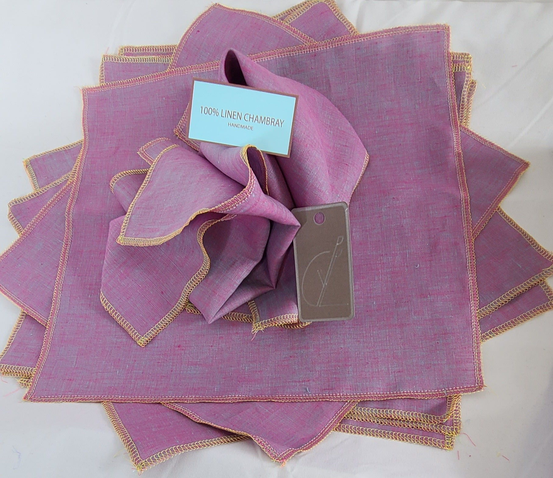 Set of purple linen napkins with gold trim on a white background