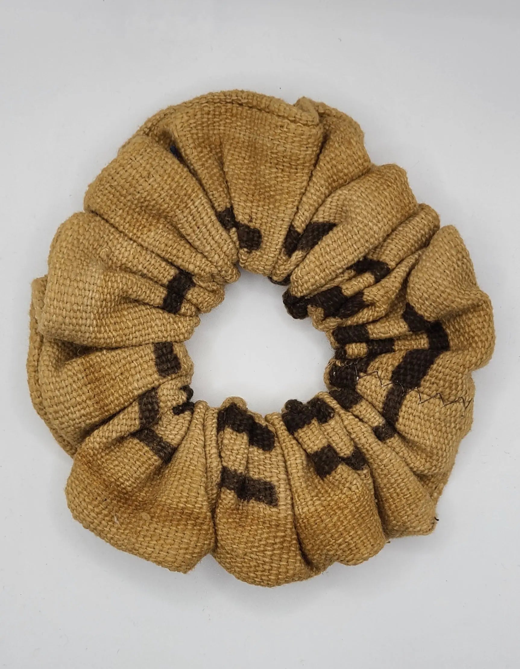 Brownish yellow scrunchie with black pattern on a white background