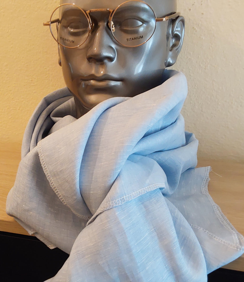 Mannequin head wearing a light blue scarf and gold-framed glasses against a beige background