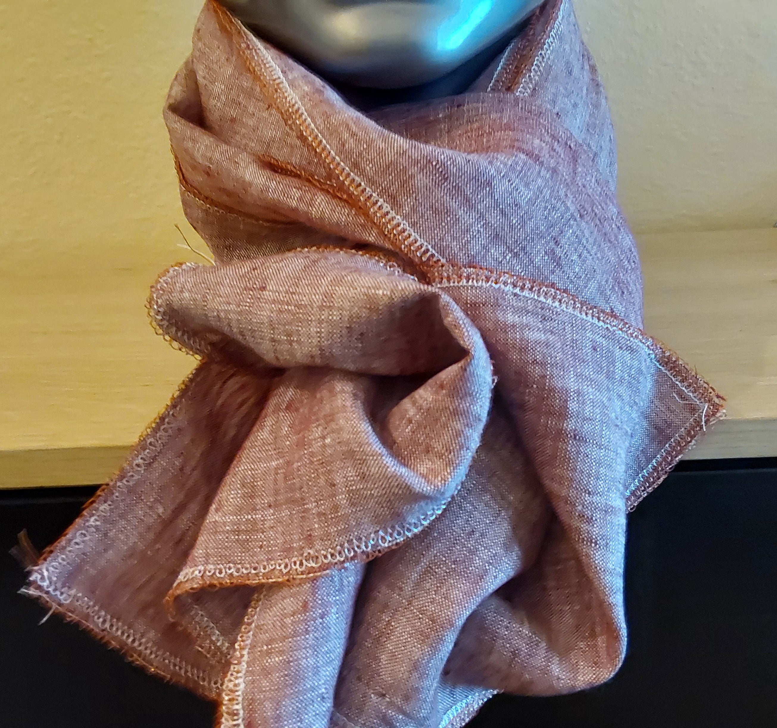 Reddish brownscarf draped over a mannequin head against a wooden background