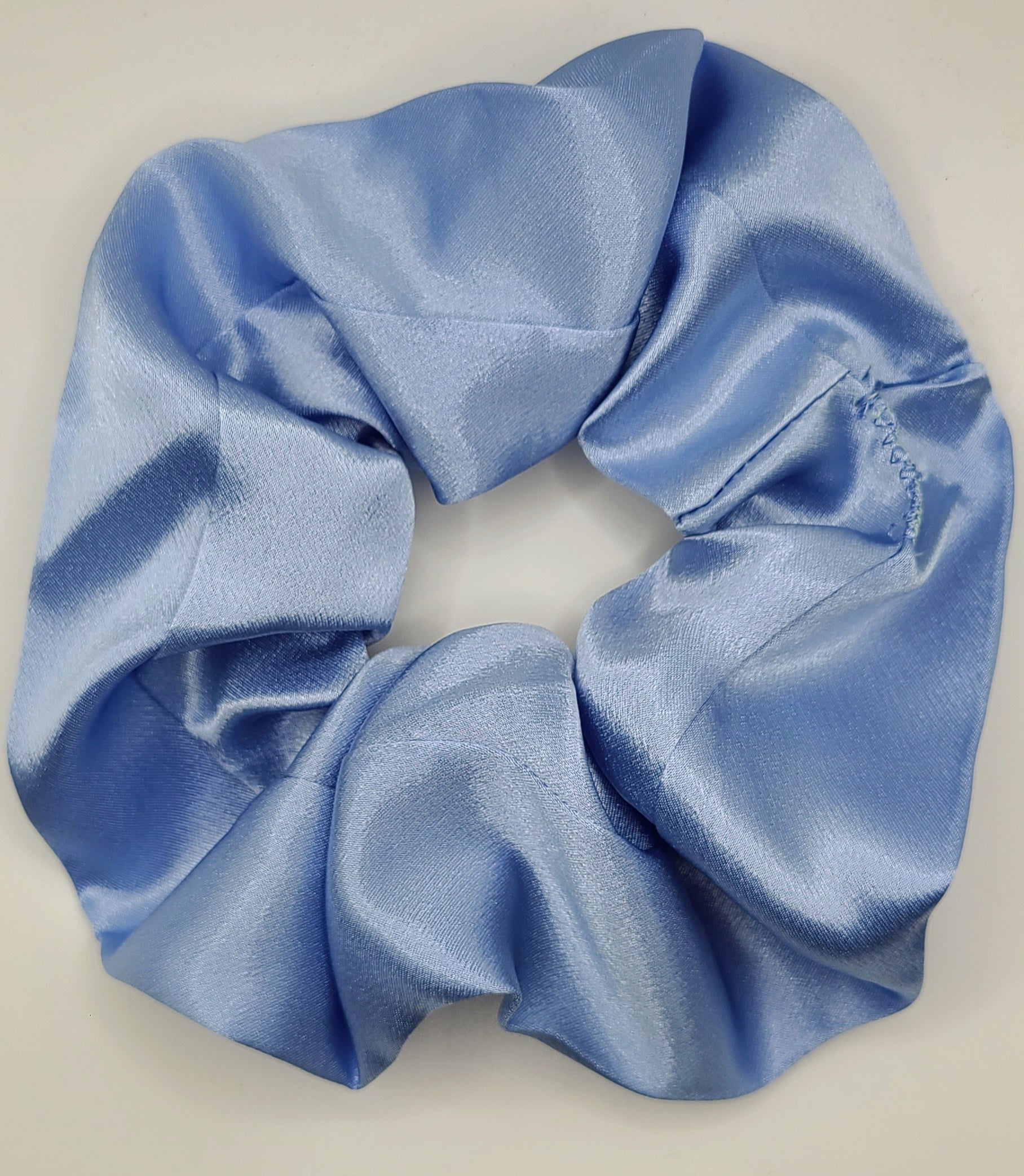 Blue satin scrunchie on a light beige background
