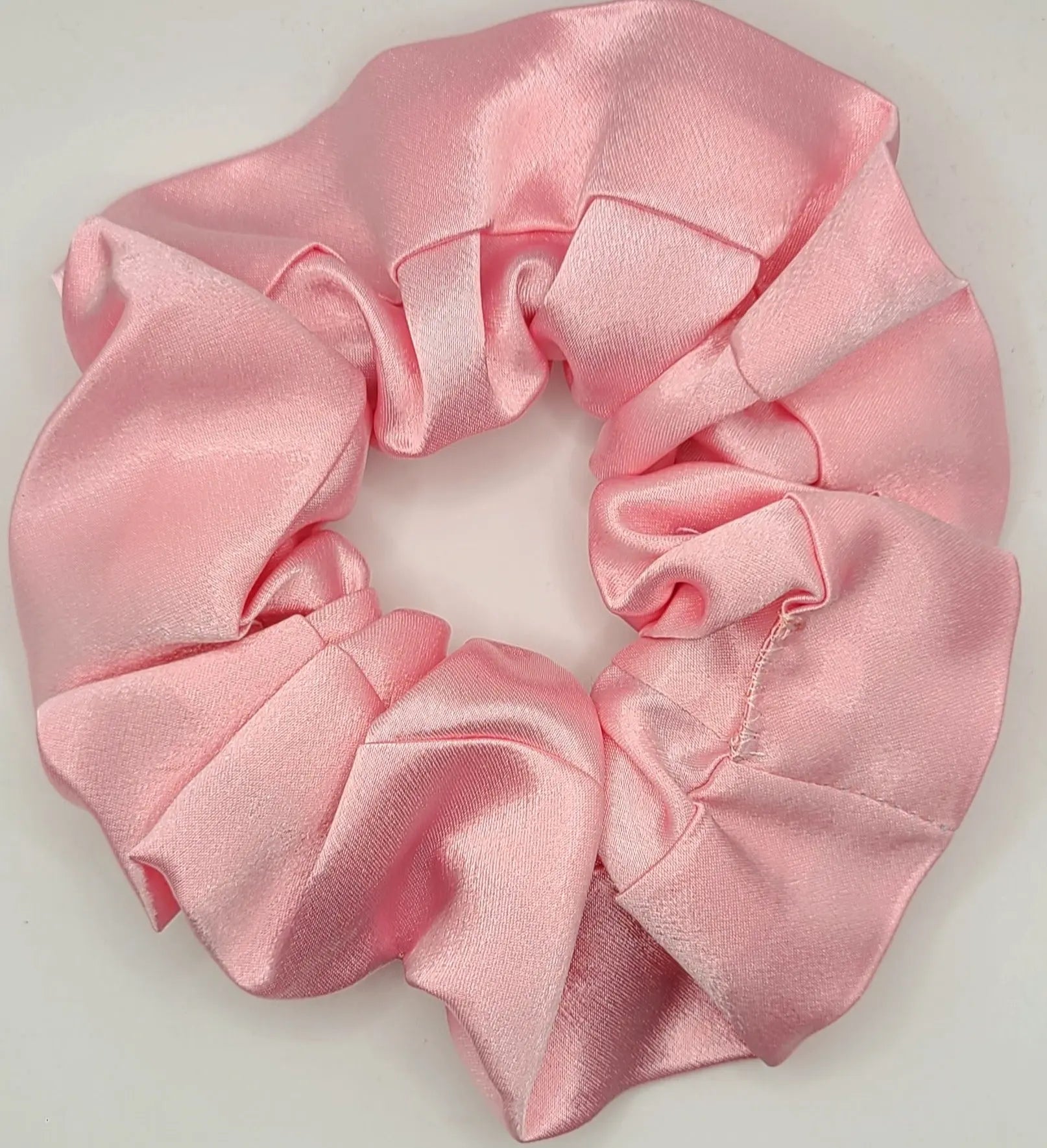 Pink satin scrunchie on a light gray background