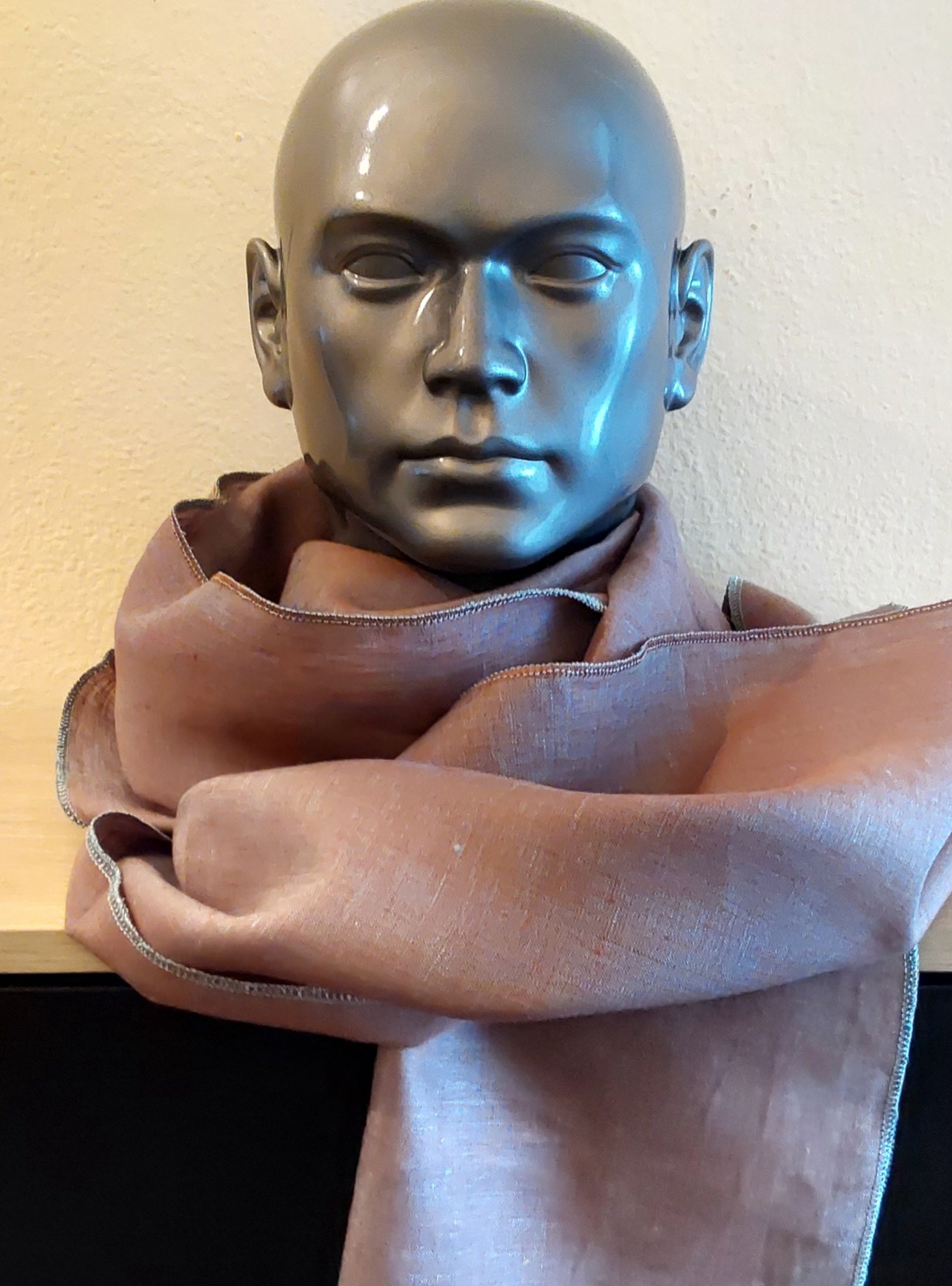 Mannequin head with a brown scarf on a plain background