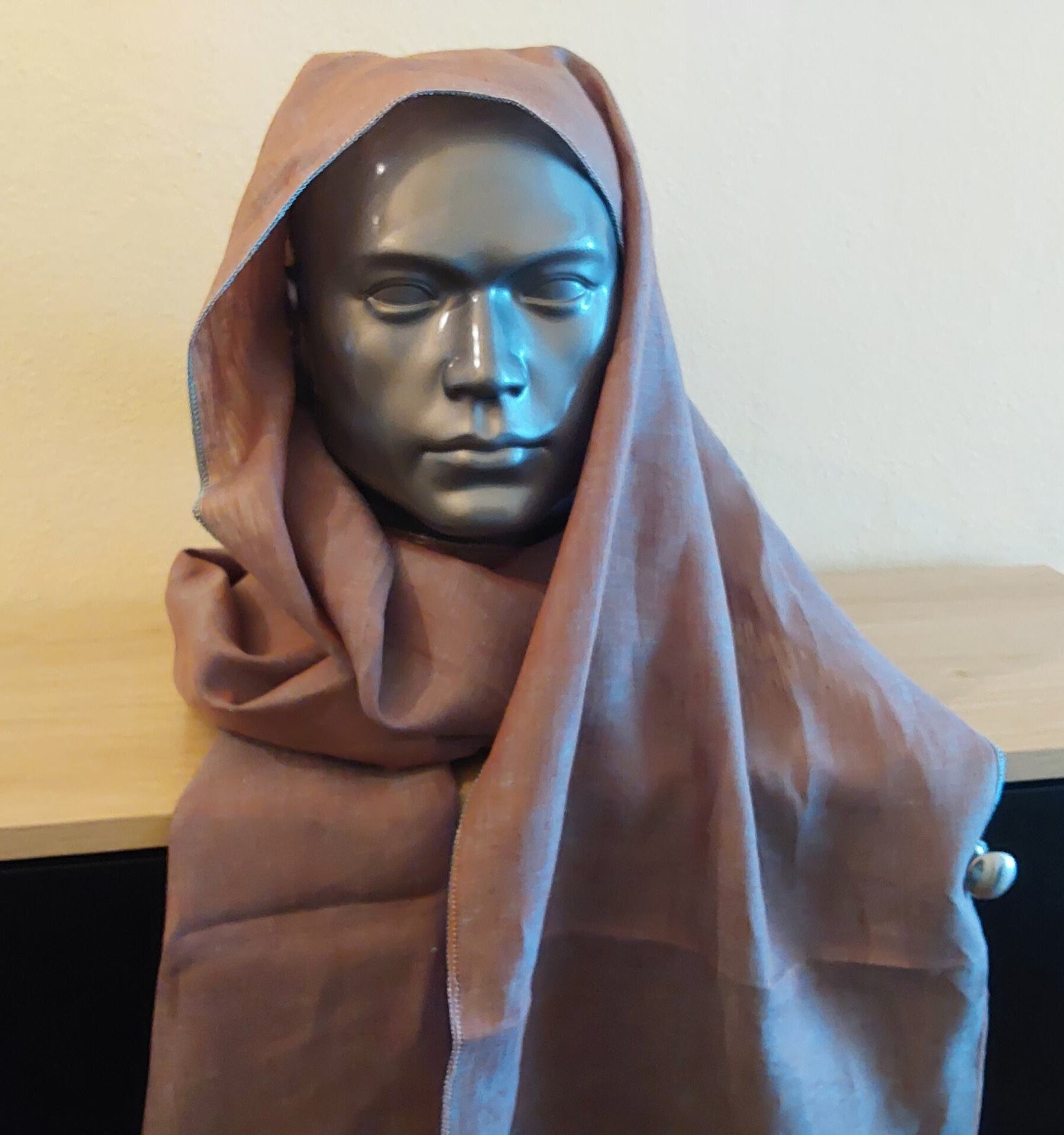 Mannequin head with a brown hood on a neutral background