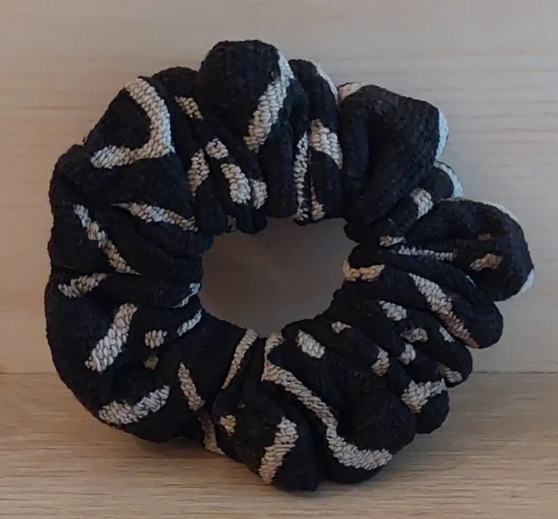 Black and beige patterned scrunchie on a wooden surface
