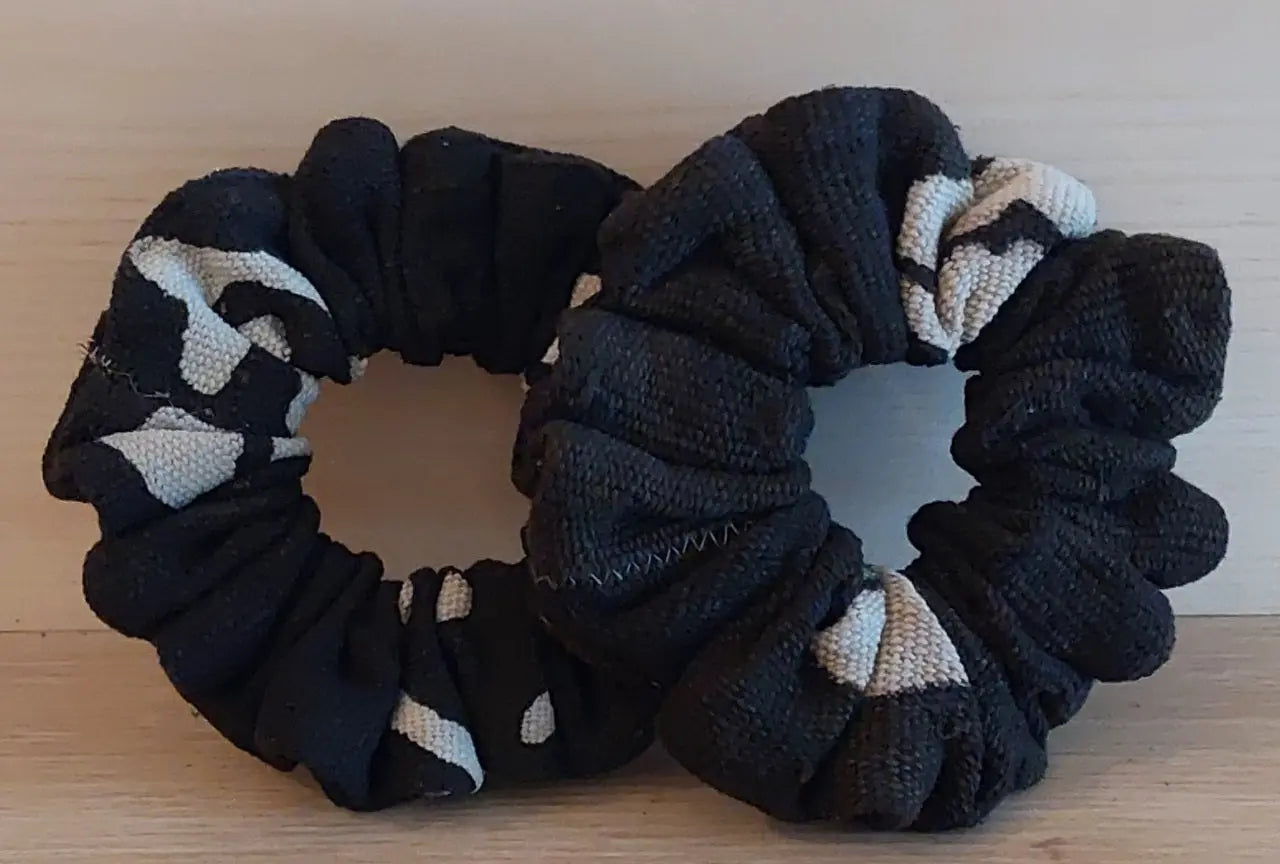 Two black scrunchies with geometric patterns on a wooden surface